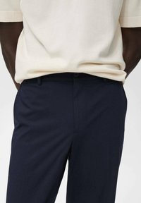 Marineblaues Hosen mit strukturiertem Stoff, Slim-Fit-Schnitt, klassischem Bund und Fronttaschen. Mit einem passenden Knopfverschluss akzentuiert.