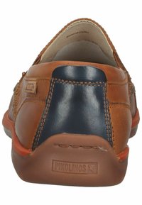 Zapato de cuero marrón con un acento azul marino, con un diseño texturizado y costuras visibles. Logo de Pikolinos en el talón. Forma redondeada.