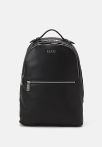 Sac à dos en cuir noir avec un design arrondi. Comprend une poche zippée à l'avant, des accessoires en métal et une poignée supérieure pour le transport. Logo affiché à l'avant.