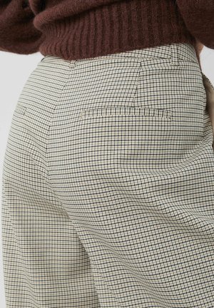 Pantalon à carreaux beige et bleu marine avec une coupe décontractée. Comprend deux poches arrière, un tissu texturé et des lignes épurées.