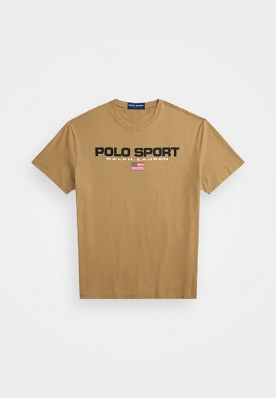 T-shirt de algodão bege com decote redondo, apresentando "POLO SPORT" e "RALPH LAUREN" em preto, além de um pequeno detalhe da bandeira americana.
