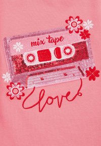 Rozā audumam ir sekmētā kasetes dizains ar ziedu akcentiem un izšūtiem vārdiem "mix * tape" un "mīlestība" sarkanā krāsā.