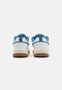 Baskets blanches et bleues avec une semelle en caoutchouc, dotées d'une tige texturée et d'un logo Puma proéminent sur le talon. Design arrondi avec col rembourré.