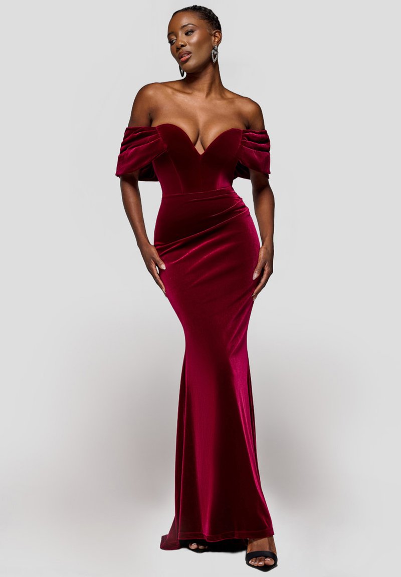 Robe en velours bordeaux avec manches décolletées, corsage ajusté et jupe fluide. Texture lisse et silhouette élégante.