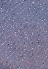Vattenavvisande tyg i mörklila med många droppar, med en texturerad yta och subtil lyster.