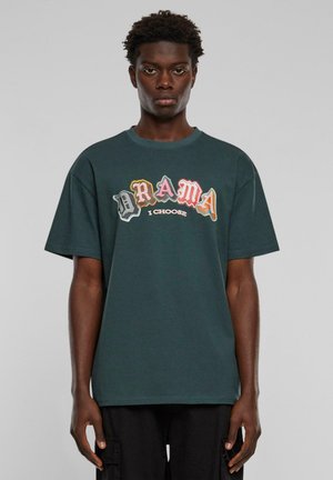 T-shirt oversize vert en coton doux, avec un imprimé graphique multicolore comportant les mots « DRAMA I CHOOSE » à l'avant.