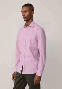Helles rosa Karohemd mit Button-Down-Kragen, langen Ärmeln und vorderen Knöpfen. Verfügt über einen seitlichen Schlitz und ein kleines Etikett am Saum.