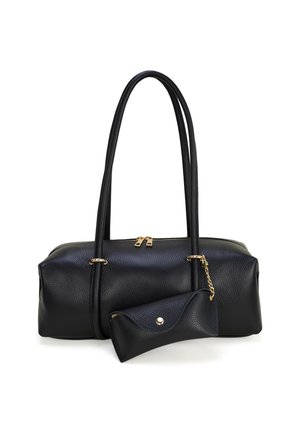 Zwarte leren handtas met lange hengsels en een aangehechte kleine bijpassende tas met gouden ketting en knoopsluiting op witte achtergrond.
