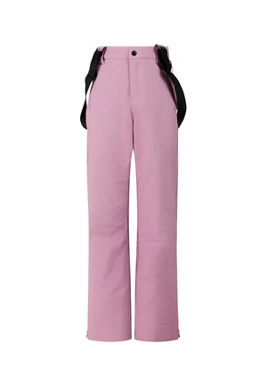Jong persoon draagt witte zonnebril, beige top met lange mouwen, roze sneeuwbroek met zwarte bretels en beige laarzen, staand tegen een effen achtergrond.