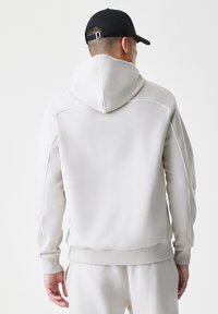 Ανοιχτού γκρι φούτερ από μαλακό ύφασμα, με κουκούλα, ραμμένα μανίκια και τελείωμα. Αντίθεση ραφής στους ώμους και τα πλάγια.