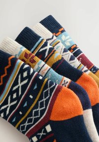 Pestrofarebné ponožky s geometrickými vzormi na námornom základe, s živými akcentmi v oranžovej, modrej a krémovej farbe. Mäkko pletená textúra.