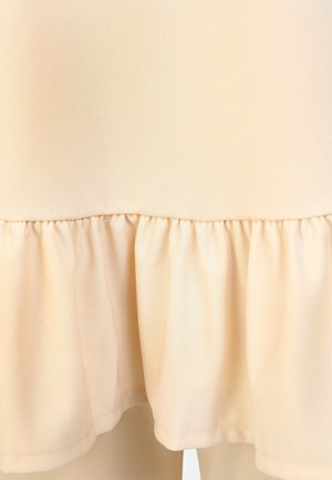 Lichtbeige stof met een gerimpelde zoom en een zachte textuur. Het ontwerp is eenvoudig en ongekunsteld, zonder zichtbare patronen of accenten.