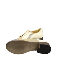 Scarpe stringate con tomaia crema, accenti beige texturizzati e una striscia metallica, dotate di tacco basso impilato e suola con motivo.
