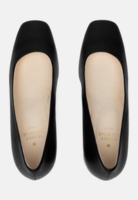 Ballerines en cuir noir avec un orteil carré, texture lisse et semelle intérieure beige clair arborant un logo discret.