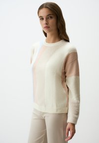 Maglione a maglia con collo rotondo, caratterizzato da toppe geometriche in crema, rosa chiaro e azzurro chiaro; tessuto testurizzato con orlo e polsini a coste.