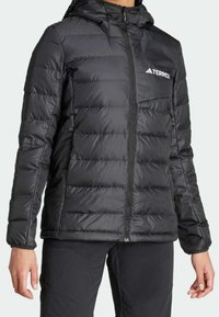 Doudoune noire avec capuche, dotée d'un design matelassé, d'une fermeture éclair et du logo Terrex sur la poitrine gauche. Tissu lisse et réfléchissant.