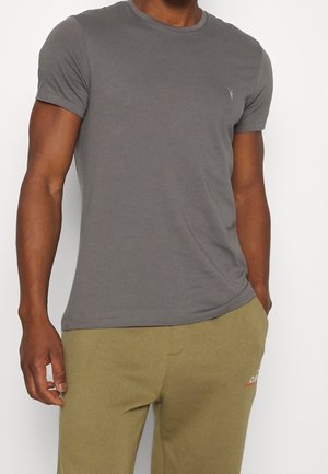 Grå T-shirt med korte ærmer lavet af blødt stof med rund hals og et lille logo på brystet, kombineret med olivengrønne bukser.