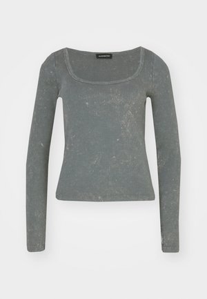 Dlhý rukáv rebrový top v jemnej zelenej farbe s širokým štvorcovým výstrihom a jemnou textúrou. Má priliehavý strih a mäkkú látku.