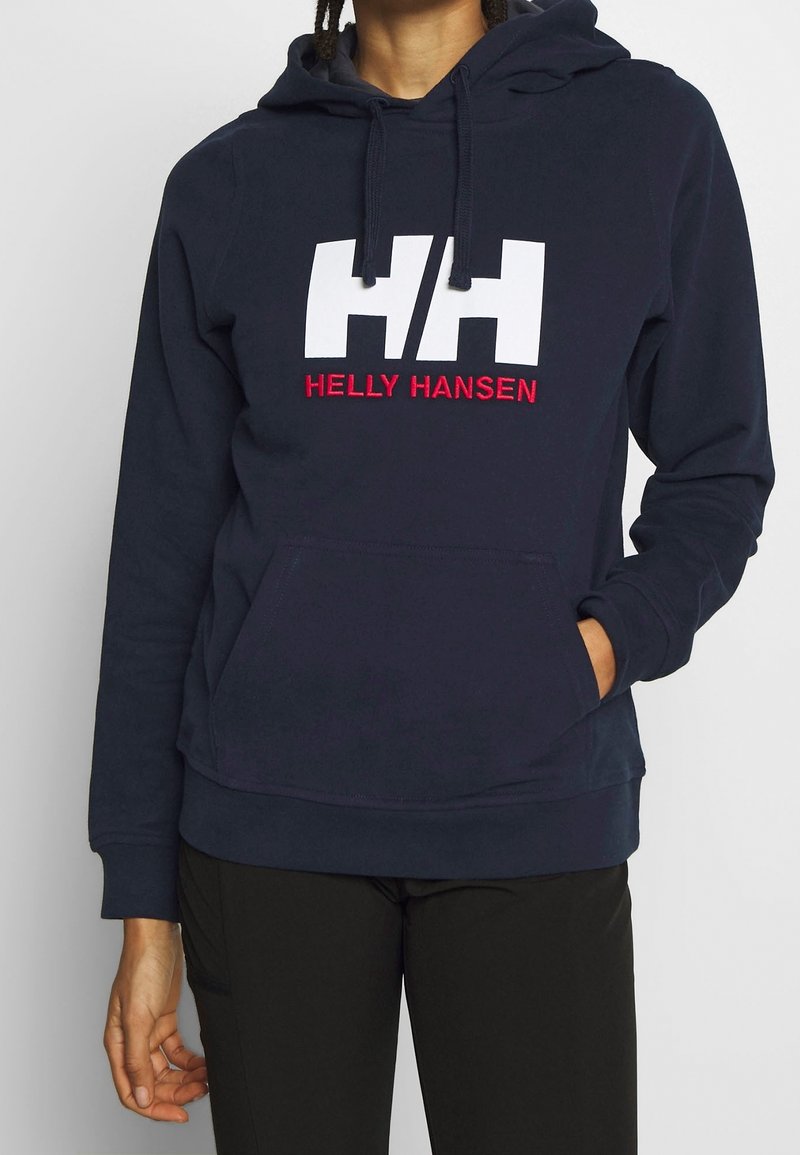 Mörkblå hoodie med framficka, prydd med vit "HH" logotyp och röd "HELLY HANSEN" text. Tillverkad av bomull med en mjuk känsla och justerbar huva.
