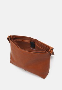 Brun skuldertaske i læder med glat tekstur, lynlåsforlukning øverst og en enkelt rem. Indvendigt er der en enkel foring og et logomærke.