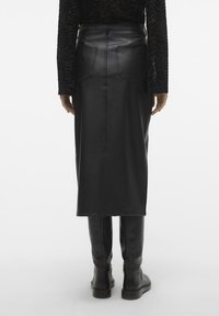 Svart läder midi kjol med bakfickor, vertikala sömmar och en figursydd silhuett, tillsammans med knähöga svarta stövlar.