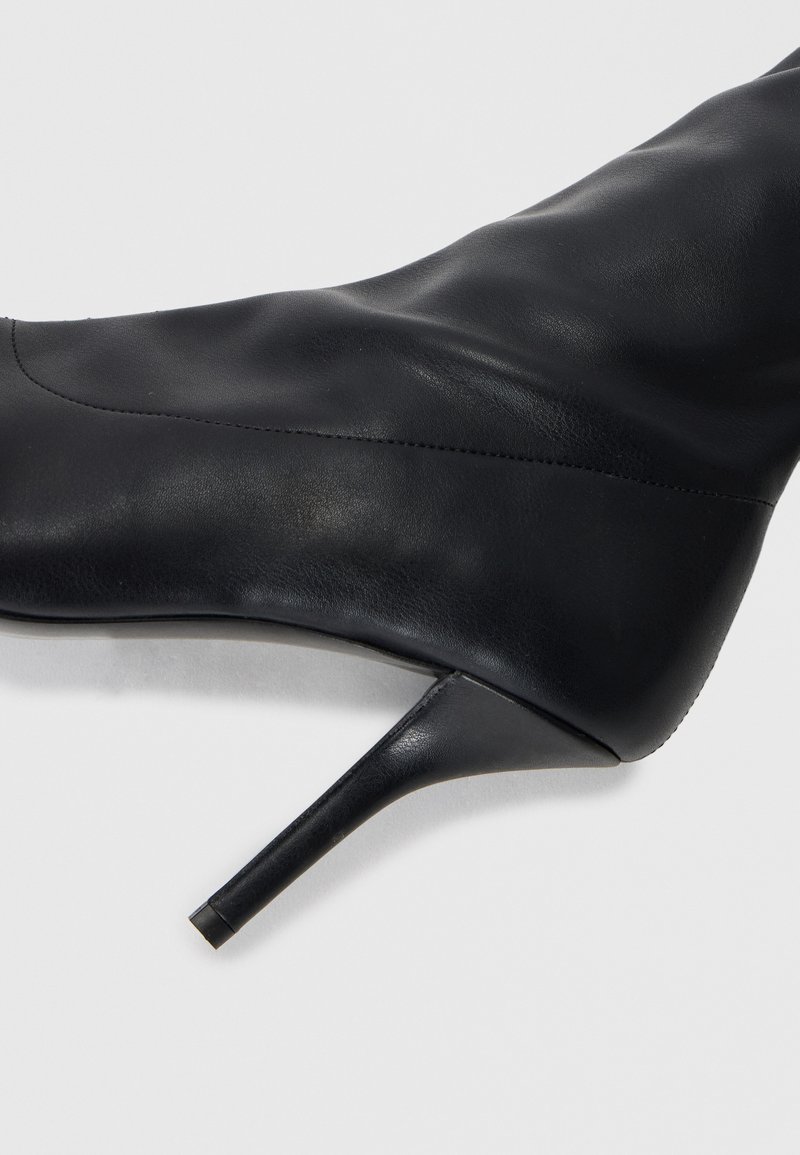 Schwarze Leder-Stiefel mit hohen Absätzen, glatter Textur, spitzer Zehenpartie und schmalem Stiletto-Absatz. Besitzt minimale Nähdetails.