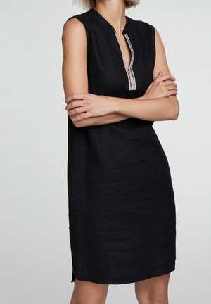 Robe sans manches en lin noir avec col montant et demi-patte de boutonnage, ornée de coutures décoratives sur le devant. Texture lisse.