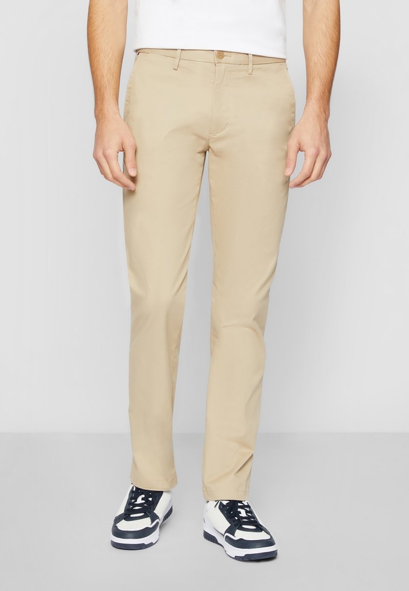Chinos beige clair en coton lisse. Présentent une coupe droite, des poches latérales et une fermeture à un bouton à la taille.