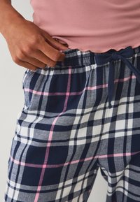 Marine ruitbroek met witte, grijze en roze lijnen, voorzien van een elastische tailleband en een trekkoord. De stof lijkt zacht en comfortabel.