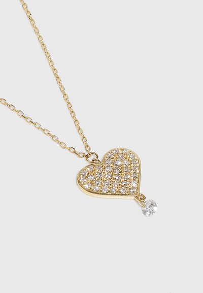 Zelta sirds kulons ar kristālu akcentiem, ar tekstūrētu virsmu un piekariņu ar skaidru dārgakmeni apakšā. Ķēdes posmi ir ovālas formas.