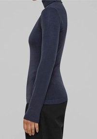 Pull col roulé bleu marine à coupe ajustée. Tissu tricoté doux, manches longues, poignets et ourlet côtelés. Texture lisse sans motifs visibles.
