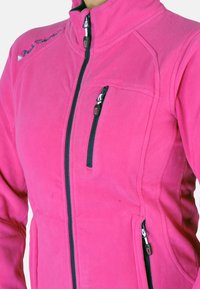 Veste en polaire rose avec un col montant, devant zippé et deux poches latérales. Présente des accents marine et une broderie de logo sur l'épaule.