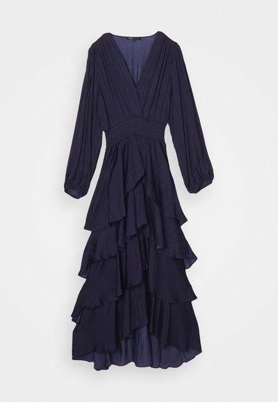 Vestido largo de manga larga en color navy con un escote en V profundo, cuerpo smock y dobladillo de volantes en capas. Confeccionado con una tela ligera y de textura suave.