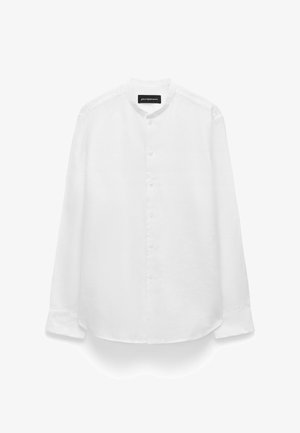 Chemise blanche à manches longues avec boutons, col mao et une poche poitrine, présentée sur un fond blanc.