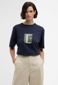 T-shirt de algodão azul-marinho com um gráfico central de uma lata de tinta com riscas coloridas e texto. Corte relaxado com mangas curtas.