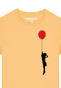 Geelt katoen t-shirt met een zwarte silhouet van een kind dat een rode ballon vasthoudt, met details van de glans van de ballon.
