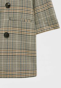 Dvojité sako v hnědém, čern�ém a krémovém kostkovaném vzoru, s velkými černými knoflíky a náprsní kapsou. Měkký texturovaný materiál.