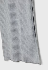 Tessuto a coste grigio chiaro con strisce verticali e orlo scallopato, dotato di uno spacco laterale per un ulteriore dettaglio e texture.