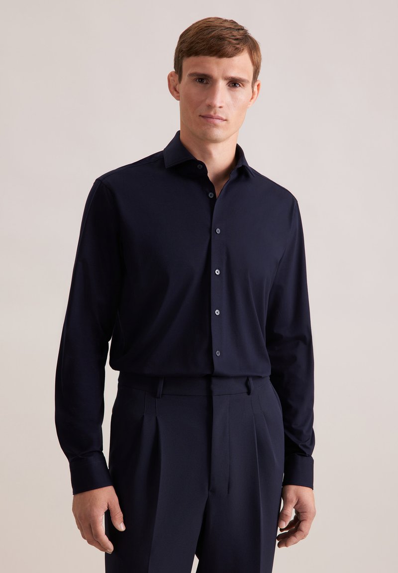 Camicia a maniche lunghe blu navy realizzata in un tessuto liscio, caratterizzata da un colletto classico, chiusura a bottoni e un design slim fit. Texture con una leggera lucentezza.