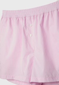 Chemise rayée rose avec ceinture élastique, dotée d'une patte de boutonnage et d'un tissu lisse et léger, offrant une coupe décontractée.