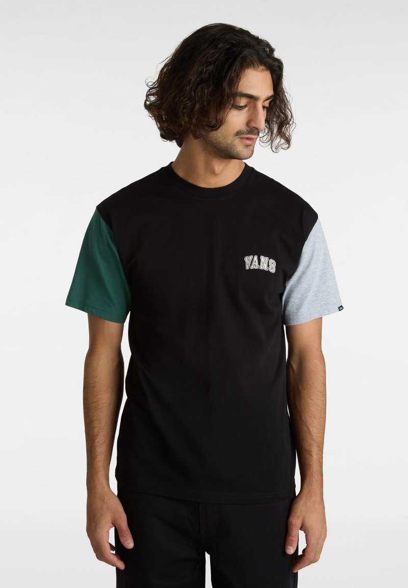 Svart bomull t-shirt med gröna och grå korta ärmar, med "VANS" logotypen på bröstet. Avslappnad passform med rund hals.