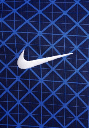 Tissu bleu à motifs présentant un design géométrique avec des triangles sur un fond sombre. Comprend un logo Nike brodé en blanc.