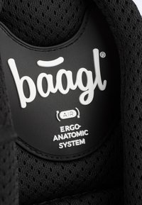 L'etichetta nera ergonomica presenta un testo bianco che recita "baagl AIR ERGO-ANATOMIC SYSTEM" su una superficie testurizzata con uno sfondo in rete.