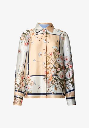 Blouse boutonnée à manches longues avec une base pêche pâle et crème, ornée d'impressions florales pastel et d'accents de bordure foncés.