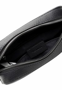 Interno di una borsa in pelle nera con una finitura testurizzata, apertura con zip e una piccola tasca interna. La fodera è in tessuto scuro.