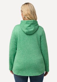 Grön textured hoodie med dragsko och en melerad mönstring. Designen inkluderar långa ärmar och en något rundad nederkant.