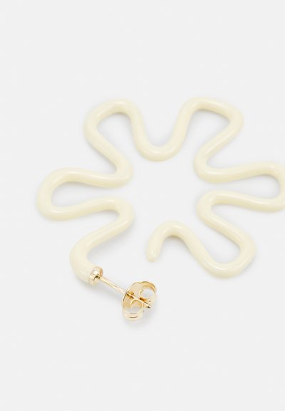 Kurvige cremefarbene Ohrringe in wellenförmigem Design, mit einem goldfarbenen Stecker und einem sicheren Verschluss. Glatte Textur und minimalistischer Stil.