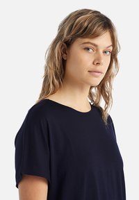 T-shirt blu navy con vestibilità rilassata, maniche corte, scollatura rotonda e trama di tessuto liscia. Dettaglio di drappeggio sottile.