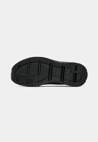 Black athletic shoe sole with varying tread patterns, grooves, and ridges. Features brand logo and reinforced sections for traction.