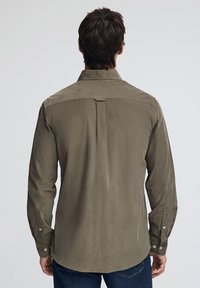 Långärmad skjorta i olivgrön färg med spetsig krage, knappärmar, en central ryggveck och en slät textur.